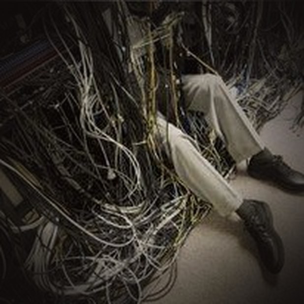 Technician tangled in a mess of network cables — the reality of hands-on IT